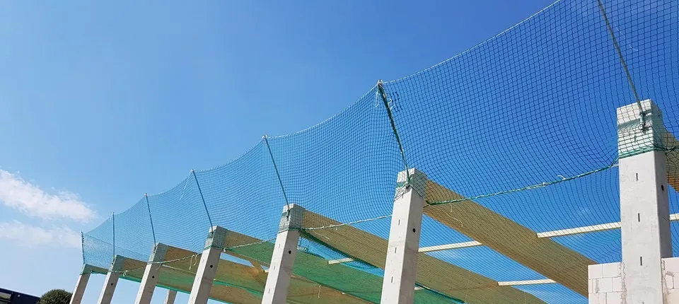 Zaščitna fasadna mreža, napeta ob gradbeni konstrukciji pod modrim nebom