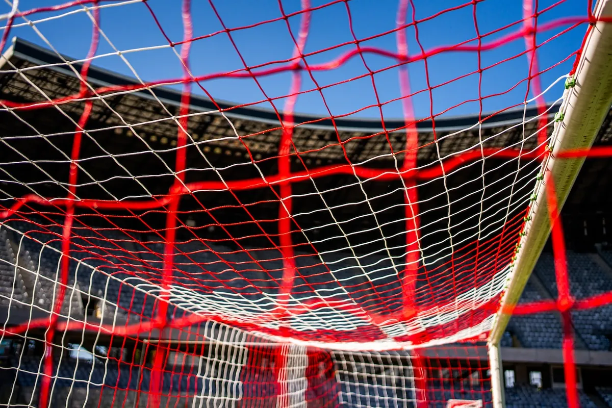 Dvobarvna rdeče-bela mreža nogometnega gola, posneta od znotraj
