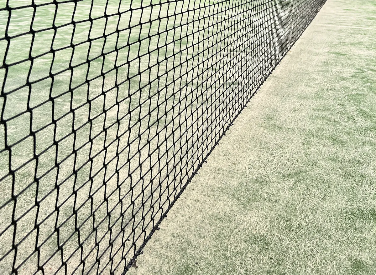 Črna mreža za padel, napeta prek igrišča v perspektivi