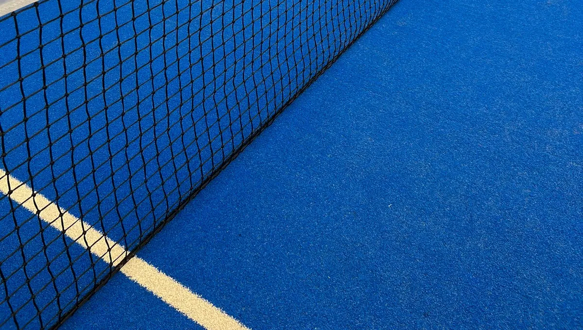 Črna padel mreža z drobnimi okenci nad modro igralno površino