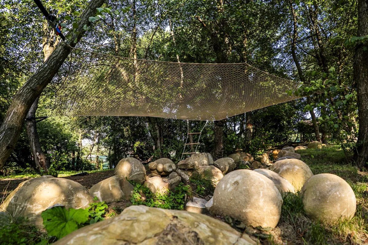 Bež viseča mreža hamak, razpeta med drevesi nad kamnitimi oblami