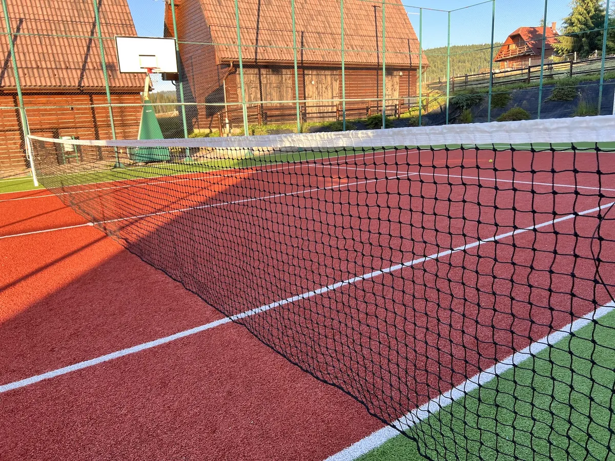 Napeta črna teniška mreža z belim zgornjim trakom na igrišču