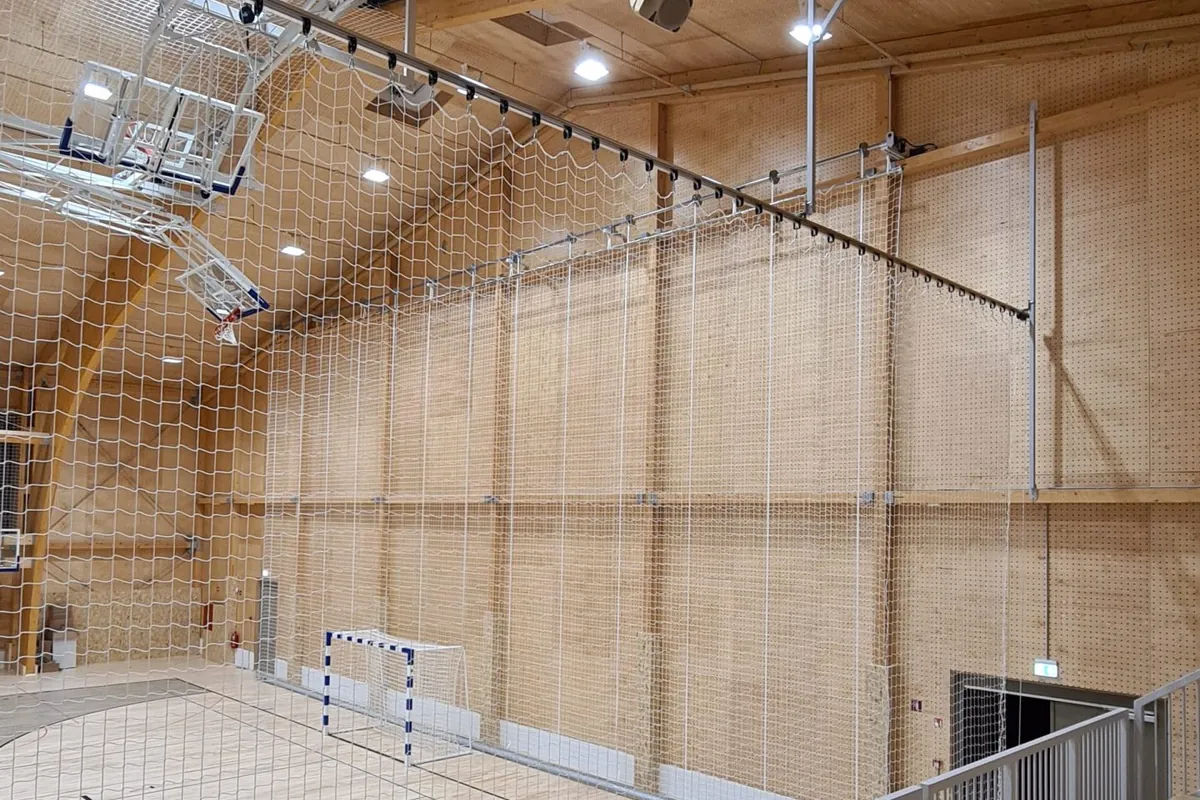 Zaščitna mreža brez vozlov, obešena po steni športne dvorane